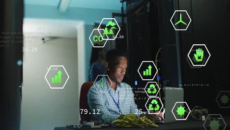 animación de iconos digitales contra ingeniero afroamericano con computadora portátil trabajando en la sala de servidores