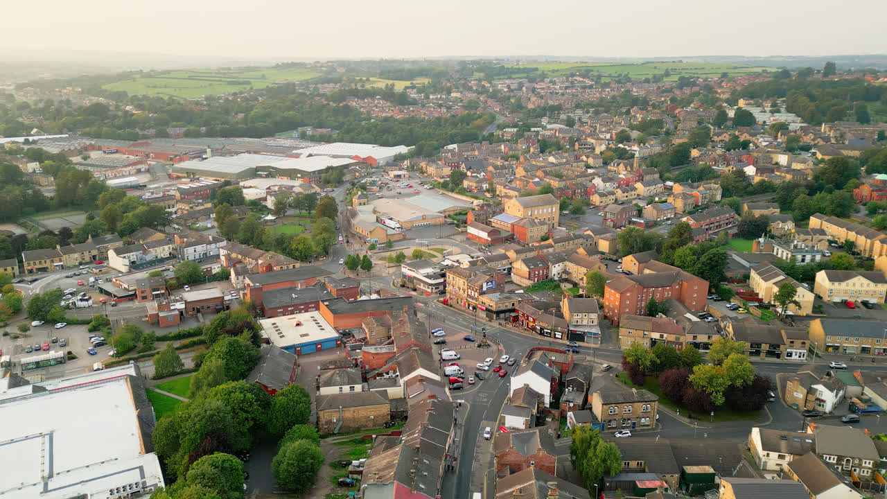 un avión no tripulado registra heckmondwike, reino unido, con edificios industriales, calles bulliciosas y el centro antiguo de la ciudad en una noche de verano