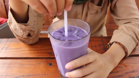 una mujer disfruta de hielo púrpura en un café de madera