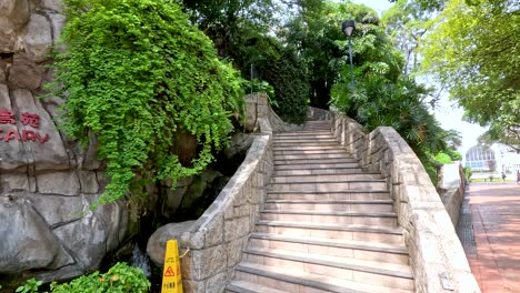 escaleras de piedra en un jardín exuberante con un aviario