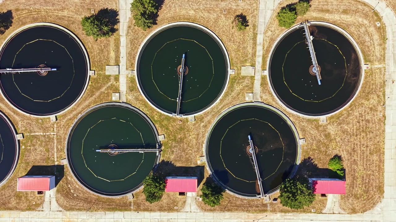 Water treatment facility with several circular tanks located in a grassy area during daylight hours