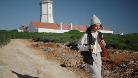 girl traveling lighthouse island with backpack alone. beautiful tourist walking