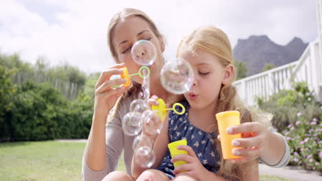 mother and daughter blowing bubbles in the yard happy family home