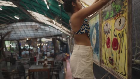 in this cinematic slow-motion shot a young woman delicately hangs abstract pictures in an art gallery