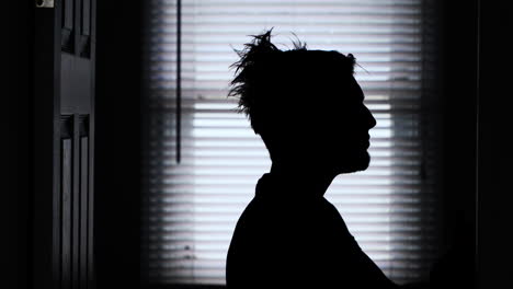 a young man's long messy hair being combed down and styled in a backlit silhouette 4k static shot