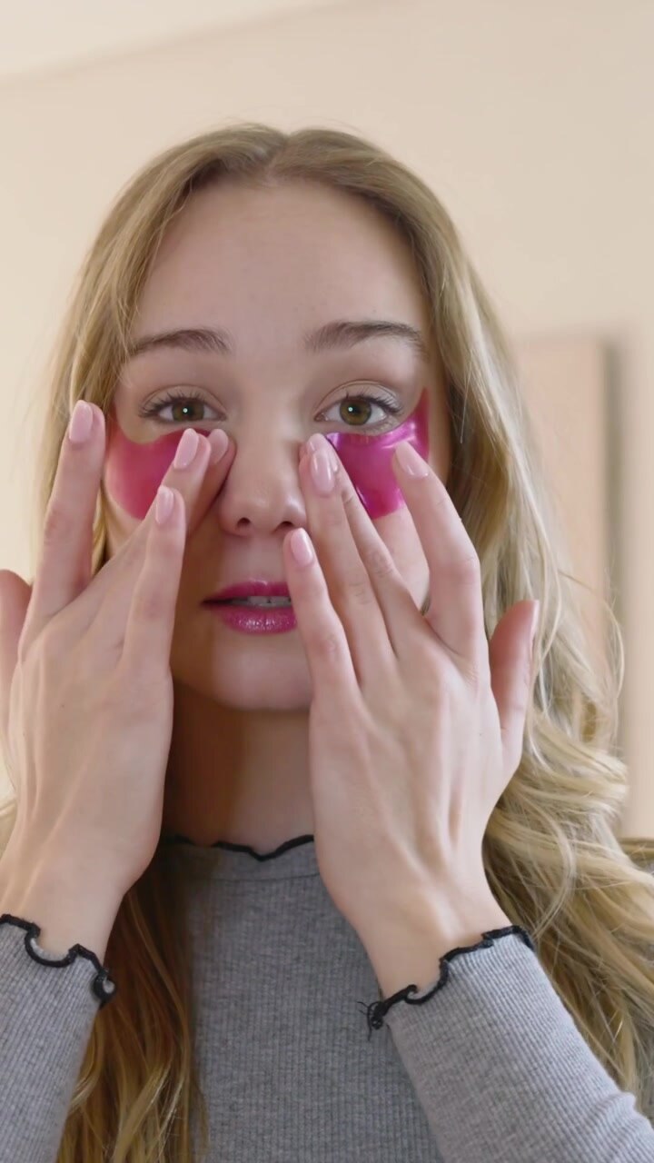 Vertical video: Lifting patch, woman in grey top placing and patting pink gel pads for demo at home