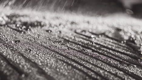 primer plano de agua rociada y gotas rodantes en una superficie negra lisa en cámara lenta