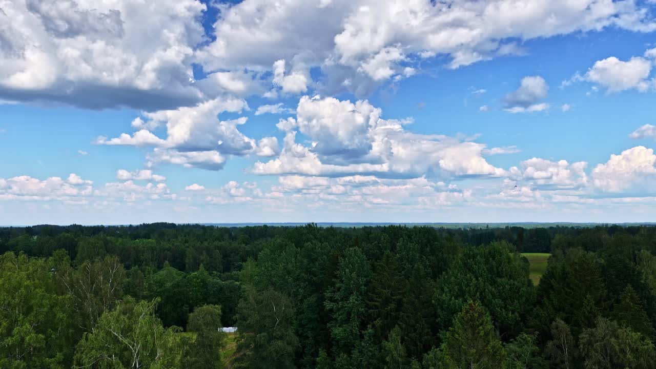 An epic aerial timelapse rises to a very high altitude, revealing the vast and beautiful patchwork landscape of the Latvian countryside with forests, fields, and moving clouds