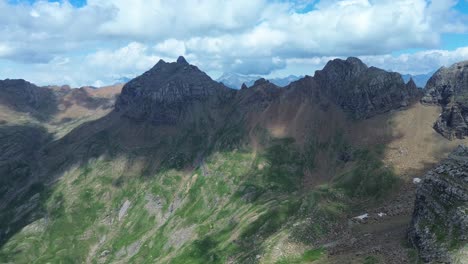 zoom in aerial shot of the green and brown ridges of the valle de ip mountain range, under a sky full of clouds