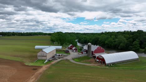 aerial view of pennsylvania countryside, showcasing rolling hills, lush green fields and charming farms. farm fields, stable and huge property. approaching shot.