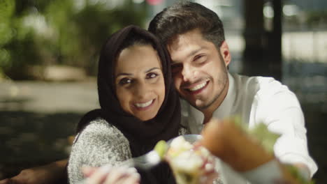 happy muslim couple showing their lunch to camera on sunny day.