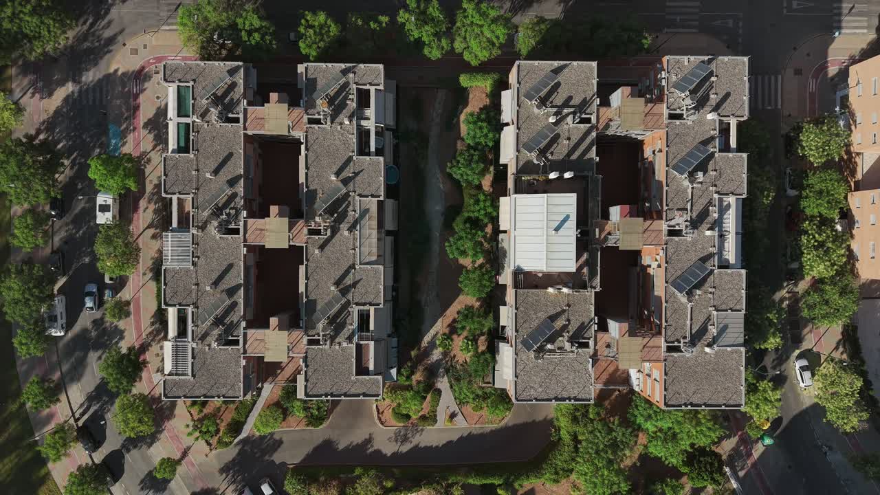 Top-down drone view revealing modern housing blocks surrounded by greenery in Málaga, Spain