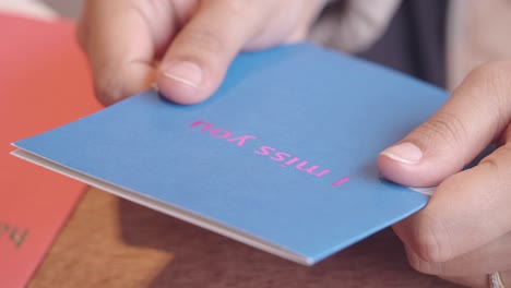 person holding a 'i miss you' card