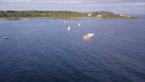 aerial shot flying over commercial fishing and lobster boats in the blue atlantic waters off the maine coast