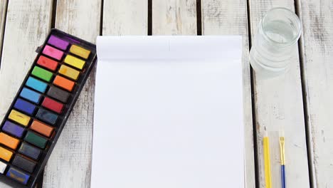 Watercolor-paints-and-paintbrush-with-blank-canvas-wooden-table