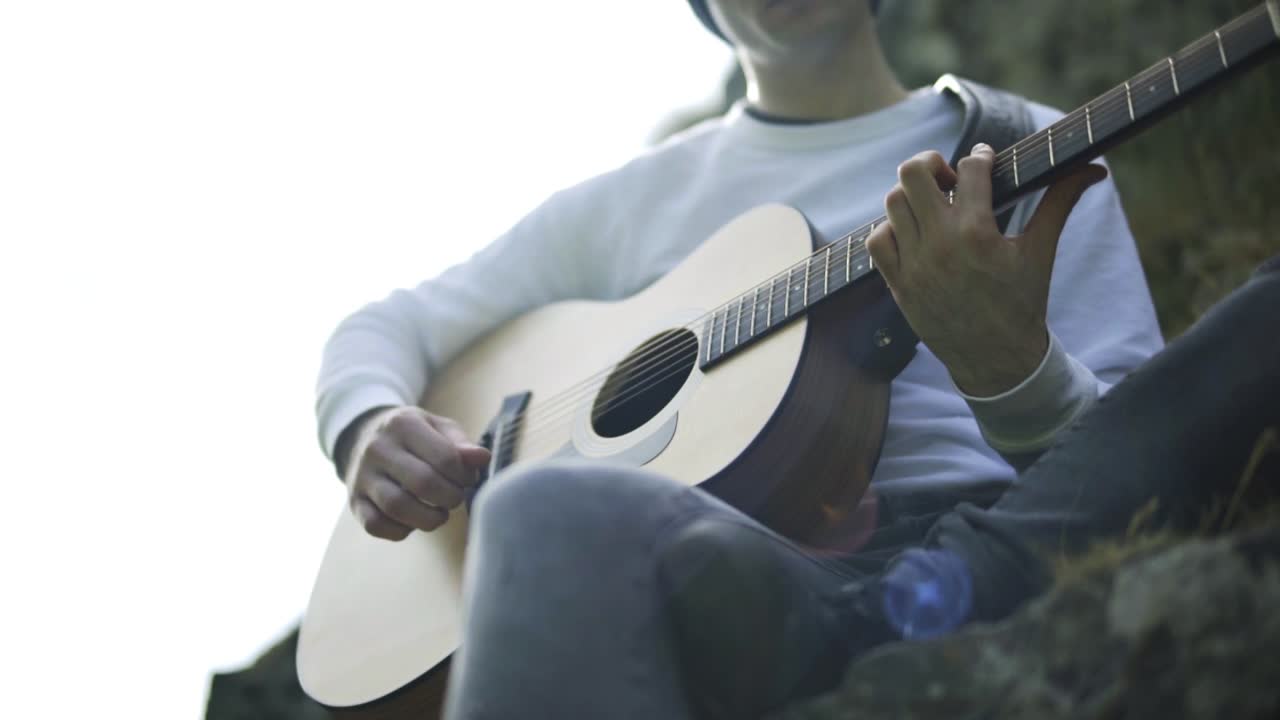 En mand der spiller guitar i slow motion udendørs.