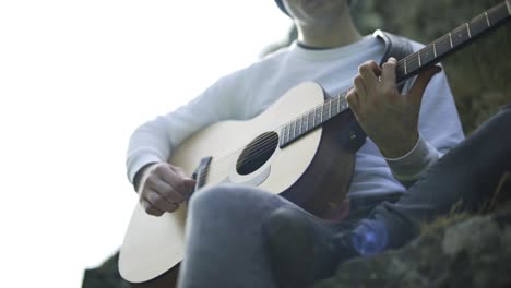 un hombre tocando una guitarra en cámara lenta al aire libre