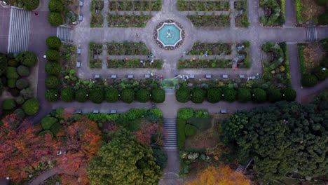 a formal garden with symmetrical design and central fountain during dusk, aerial view