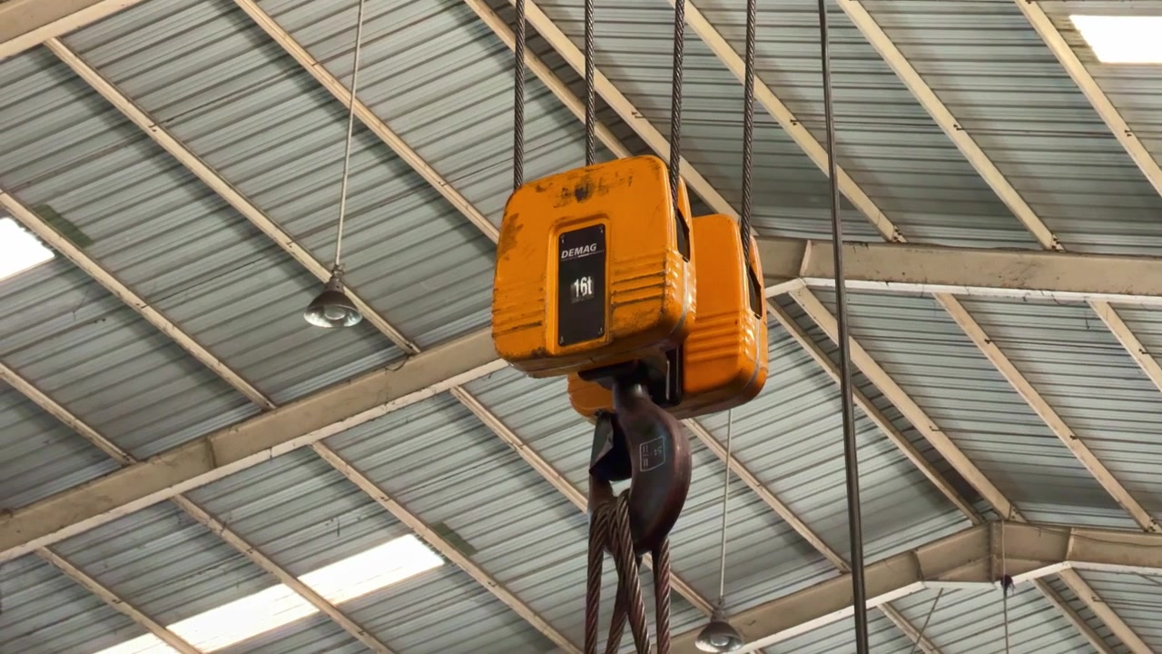 Industrial overhead crane hook with wire rope in warehouse. Manufacturing, heavy industry, and factory equipment concept footage.