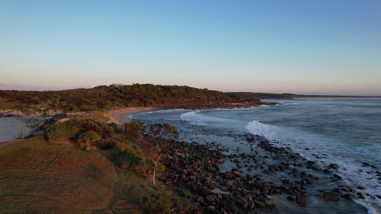 Onde che si infrangono sulla costa rocciosa all'alba.