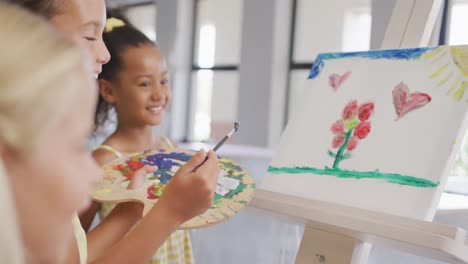 video of happy diverse girls painting during art lessons at school