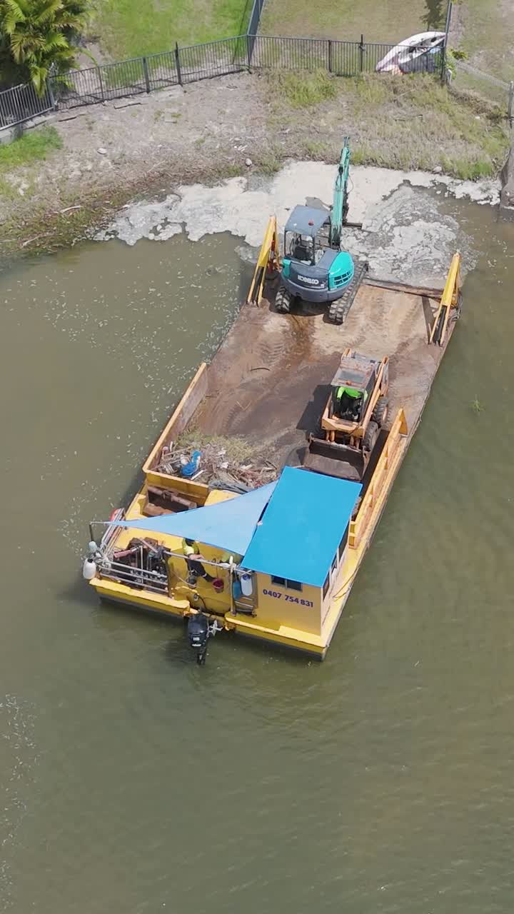 imágenes de drones capturan una barcaza con equipos de construcción trabajando en un canal cerca de casas de lujo en aguas de broadbeach