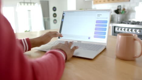 african american woman typing on laptop, showing ai chat bot screen, at home