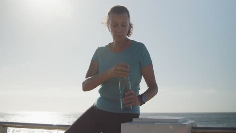 Ältere-Frau-Trinkt-Wasser-Auf-Einer-Promenade