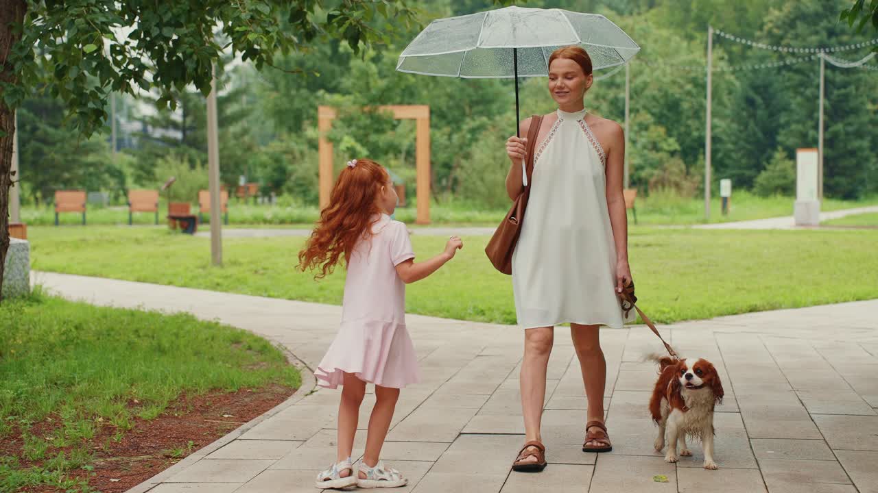 Mother, daughter, and dog enjoying a rainy day in the park