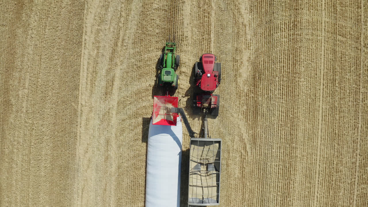 Zoom a volo d'uccello su attrezzature agricole che mietono grano, Saskatchewan, Canada.
