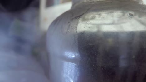botella de vidrio en una habitación ahumada con equipo informático en el fondo