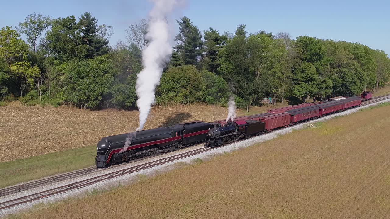 Aerial View of Antique Restored Steam Engines Warming up Blowing Smoke with freight and Passenger Cars on a siding on a Sunny Summer Day