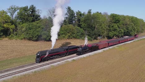aerial view of antique restored steam engines warming up blowing smoke with freight and passenger cars on a siding on a sunny summer day