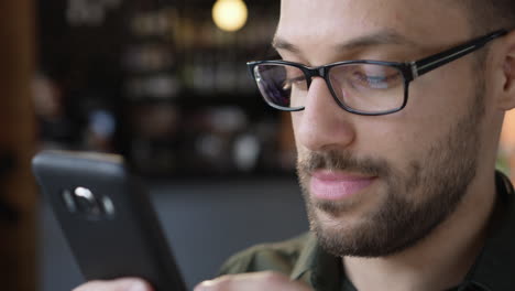 man in glasses uses smartphone closeup