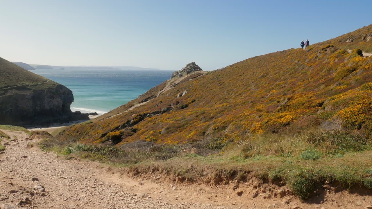 Wide angle scenic view looking down sloping gravel path and panning across beautiful Cornwall coastline
