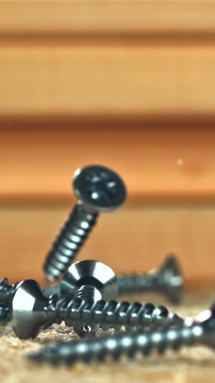 Slow Motion Close-Up of Metal Screws Dropping onto a Wooden Surface