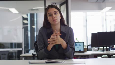 Caucasian-businesswoman-sitting-at-desk-having-video-call-gesturing