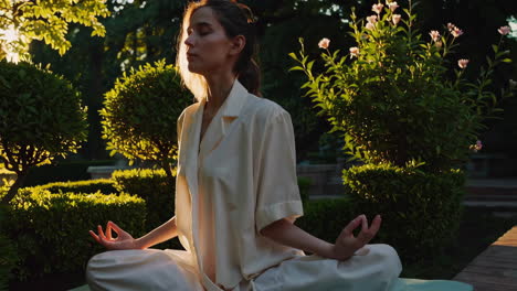 woman meditating in a garden at sunset