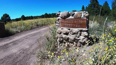 un camino rural privado está marcado con un pilar de piedra y un letrero de madera, asta de bandera, arizona