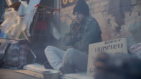 homeless man sitting on city street, shivering from cold