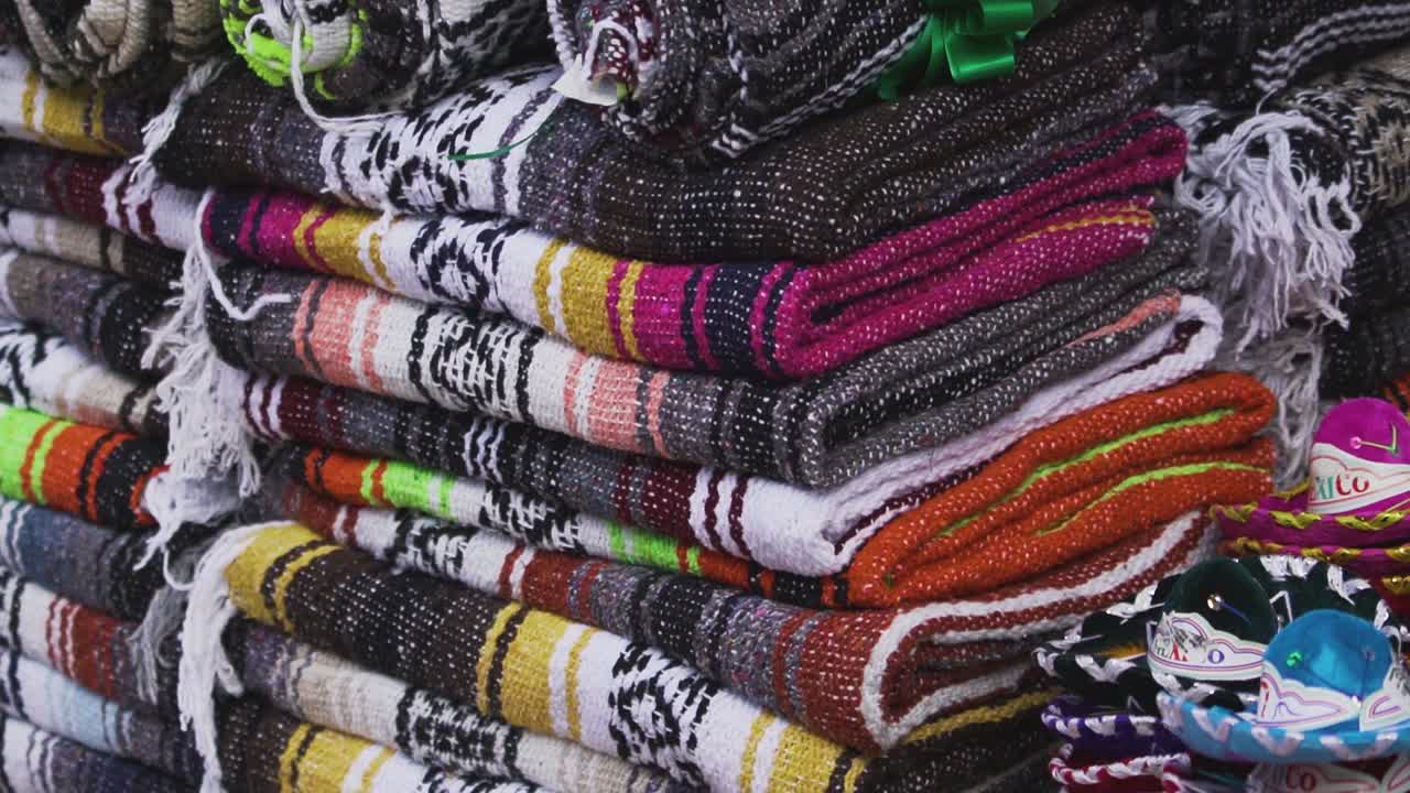 Handheld close up shot of an indigenous woman organizing serapes in Mexico