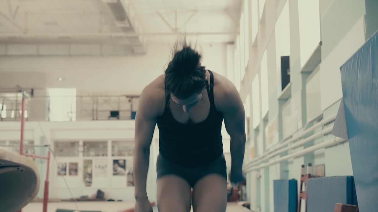 chica atlética construir en el gimnasio correr y hacer un salto mortal por delante