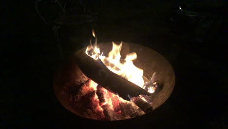 logs burning in a fire bowl on a pitch black night