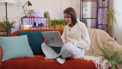 Woman-sitting-on-home-couch,-looking-at-camera,-making-video-conference-call-with-friends-or-family