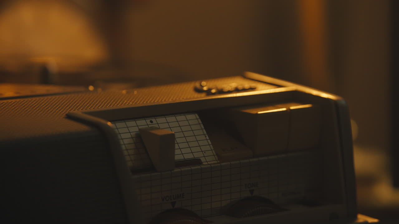 핸드 프레스는 따뜻한 빛이 있는 책상 위의 릴 투 릴 테이프 레코더에서 재생됩니다.