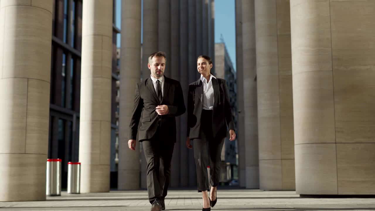 두 명의 사업가, 자신감있는 중년 남성과 공식적인 슈트를 입은 아름다운 젊은 여성이 함께 거리를 고 이야기하고, 전체 길이의