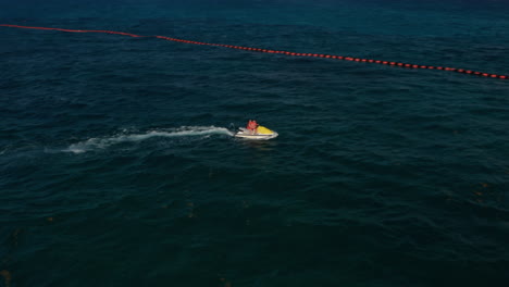 Young-couple-enjoying-the-ride-on-the-jet-ski.-Aerial-view,-tracking-shot