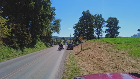 An-Amish-Horse-and-Buggy-Passing-Down-a-Country,-With-Amish-Teens,-in-Slow-Motion-on-a-Beautiful-Sunny-Day