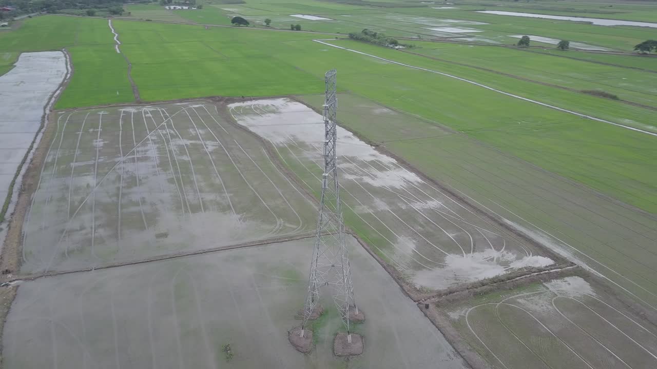 vista aérea círculo en movimiento alrededor de la columna de electricidad de alto voltaje en tierras de cultivo tailandesa