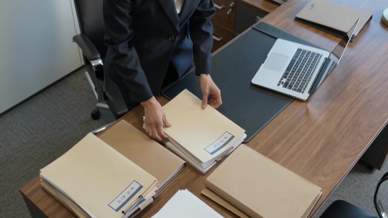 Reaching Asian woman in dark blazer sorting manila files on office desk for meeting, copy space